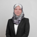 Professional portrait of a woman wearing a black blazer and patterned hijab, facing the camera with a neutral expression.